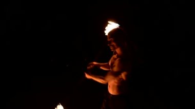Siyah pantolonlu genç bir adamın karanlığa yakın yavaş hareketi, dönen yanan bir meşalenin temsilini gösterir. Meditasyon hareket halinde. Sakin ve sarsılmaz. Ateşle çalış. Düşük anahtar