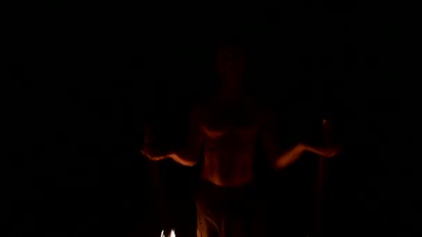 Крупный план Медленное движение молодого человека в черных штанах в полной темноте показывает представление вращающегося горящего факела. Медитация в движении. Спокойно и непоколебимо. Работа с огнем. Низкий ключ — стоковое видео