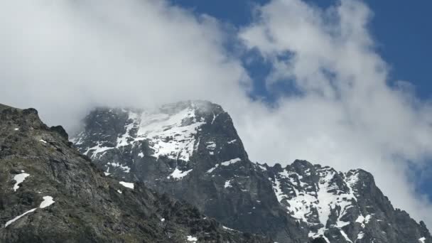 Primer plano timelapse afilada roca escarpada con manchas nevadas contra un fondo de nubes de cúmulos remolinos en un día soleado. Montaña cambio climático concepto — Vídeos de Stock