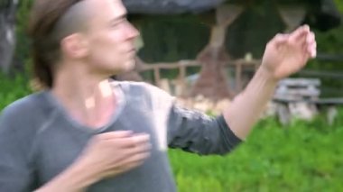 Ortalama bir plan Hint giysi ve pantolon Aladdin uygulamaları qigong bir genç adam eski bir kulübe yanında yaz aylarında qi enerji açık havada çalışırken egzersizleri yaparken