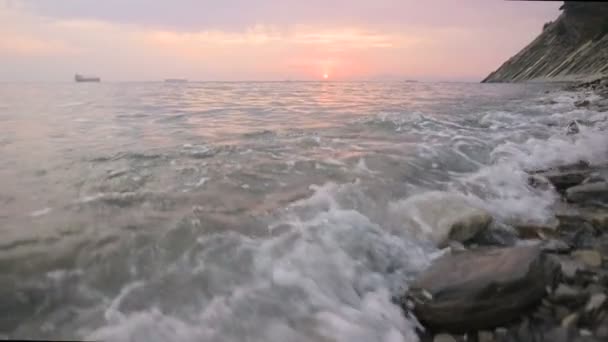 Yakın çekim yavaş hareket düşük geniş açı küçük deniz dalgaları kayalık bir plajda haddeleme. Sahil boyunca ileri ye doğru hareket edin. Sahil. Çakıl taşlı kayalık plajda akşam gün batımı — Stok video