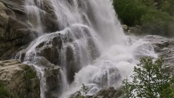 Slow motion water falls from a huge rock. Waterfall in the natural environment in cloudy weather with light rain — Stock Video
