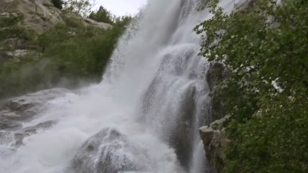 Closeup water drop and spray of a waterfall of a stormy mountain river in a green forest in slow motion with tracking wiring. The concept of global warming — Stock Video