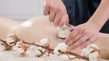 Yakın çekim bir erkek fizyoterapist genç bir kadın bir anti-selülit kalça ve uyluk masaj vermek için bir vakum kavanoz kurar. Kadın vücudunun sağlık bakım kavramı