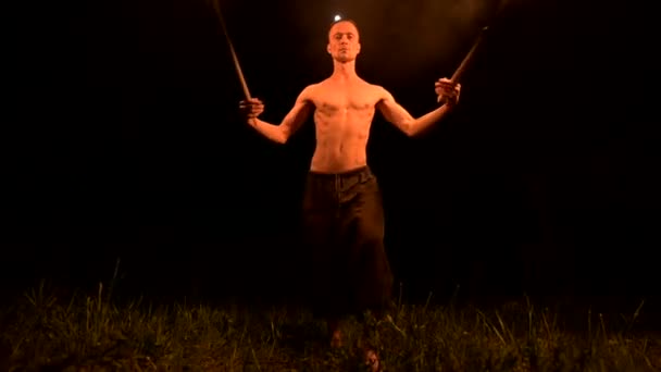 Mișcarea lentă a unui tânăr cu un trunchi gol în pantaloni negri în întuneric total arată o reprezentare a unei torțe rotative în flăcări. Meditație în mișcare. Calmă şi neclintită. Lucrează cu focul. Cheie scăzută — Videoclip de stoc