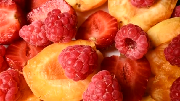 Gros plan de fraises rouges tranchées et de framboises à côté d'abricots sur une assiette. Caméra en direct. Le concept de régime alimentaire délicieux et sain et végétarisme . — Video