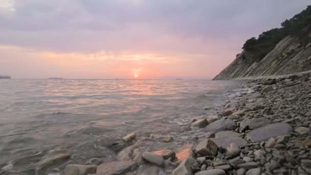 Close-up slow motion low wide angle small sea waves rolling on a rocky beach. Movement along the beach forward. Seaside. Evening sunset on a pebble rocky beach — Stock Video