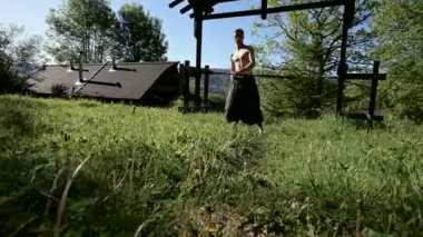 Uzun menzilli bir adamın yangın gösterisi için uzun çekim sabah eğitimi. Yeşil bir ormanın yanında açık havada güneşli bir yaz sabahı meşaleler ve zincirler ile ateş olmadan bir performans için hazırlık.