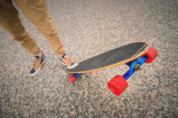 Close-up of male legs in rag sneakers on a longboard on the background of asphalt at sunset. Big skateboard with man legs. Youth leisure concept — Stock Photo, Image