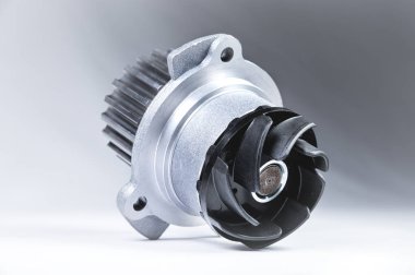 Bir degrade ile gri bir arka plan üzerinde bir motor su pompası soğutma için yeni metal otomobil pompası. Otomobil motoru için yeni yedek parça konsepti