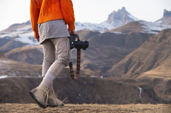Uma mão feminina segura uma câmera contra uma paisagem montanhosa — Fotografia de Stock
