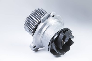 Bir degrade ile gri bir arka plan üzerinde bir motor su pompası soğutma için yeni metal otomobil pompası. Otomobil motoru için yeni yedek parça konsepti