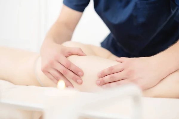 Zbliżenie ramienia masażysty mężczyzna robi hip masażu do dziewczyny w salonie spa. Koncepcja masażu i pielęgnacji ciała — Zdjęcie stockowe