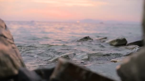 Közelképek lassú mozgás alacsony szög kis tengeri hullámok gördülő egy sziklás tengerparton. Tengerparti. Esti naplemente a kavicsos, sziklás strandon — Stock videók