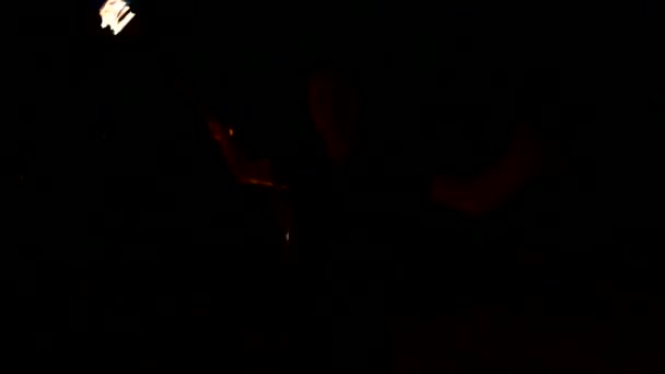 Bajo perfil. Joven macho con el pelo largo gira la antorcha ardiente al aire libre en un video nocturno negro en cámara lenta. Fakir moderno hace trucos con un personal en llamas — Vídeos de Stock