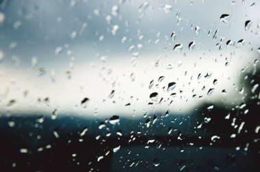 Her iki yağmur ve sisleme soyut görünümü, yağmur damlaları mavi cama cam ve bulanık manzara mavi ve yeşil geçişin üzerinde doğal arka plan damla