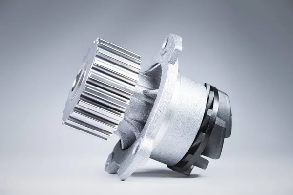 New metal automobile pump for cooling an engine water pump on a gray background with a gradient. The concept of new spare parts for the car engine