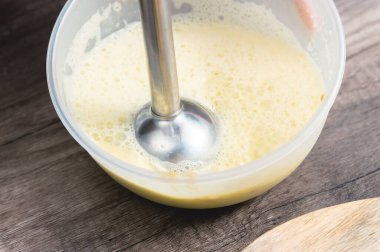 plastik bir kapta bir blender ile ev yapımı mayonez karışımı kırbaçlama yakın çekim