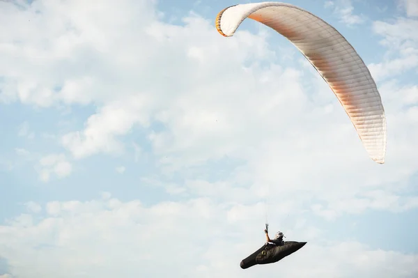 Ein Gleitschirmflieger fliegt im Kokon-Anzug auf einem Gleitschirm gegen Himmel und Wolken. Gleitschirmsportkonzept — Stockfoto