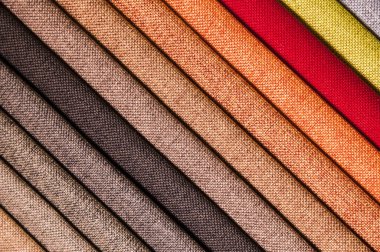 Mobilya ve giysi döşemelerinin renkli ve parlak kumaş örnekleri. Farklı renklerdeki tekstil soyut çapraz çizgilerinin paletinin yakın plan görüntüsü