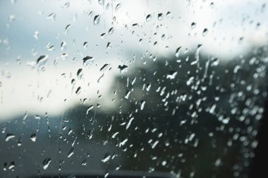 Her iki yağmur ve sisleme soyut görünümü, yağmur damlaları mavi cama cam ve bulanık manzara mavi ve yeşil geçişin üzerinde doğal arka plan damla