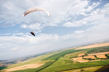 Bir yamaç paraşütü tepeler ve dağlar ile Kafkas kırsal üzerinde bir yamaç paraşütü üzerinde bir koza takım elbise gökyüzünde uçar. Yamaç Paraşütü Spor Konsepti