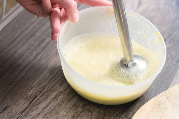 Close-up whipping the mixture of homemade mayonnaise with a blender in a plastic bowl — Stock Photo, Image