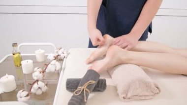 Yakın çekim bir erkek fizyoterapist bir güzellik ve sağlık spa genç bir kadına ayak ve topuklu ayak masajı yapıyor. Ayak ve vücut bakım konsepti