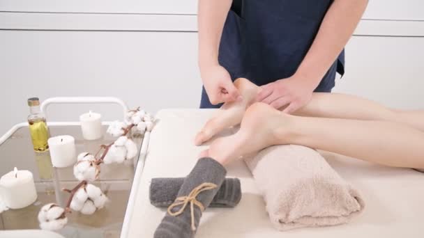 미용 및 건강 스파에서 젊은 여성에게 발과 발 뒤꿈치 마사지를하고남성 물리 치료사의 클로즈업. 풋 케어 컨셉 — 비디오