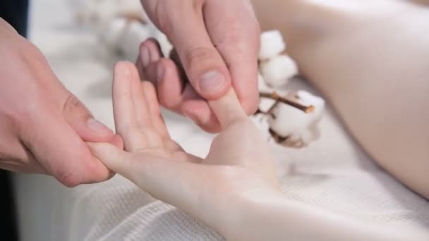 Крупним планом чоловічий фізіотерапевт робить масаж пальців і долонь молодій дівчині в масажному салоні. Професійна брошура та глибока релаксація — стокове відео
