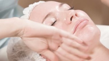 Kapalı Spa yüz masajı. Profesyonel masaj terapisti çekici bir spa salonu müşterisine yüz masajı yapıyor.