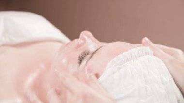 Kapalı Spa yüz masajı. Profesyonel masaj terapisti çekici bir spa salonu müşterisine yüz masajı yapıyor.