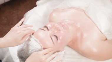 Kapalı Spa yüz masajı. Profesyonel masaj terapisti çekici bir spa salonu müşterisine yüz masajı yapıyor.