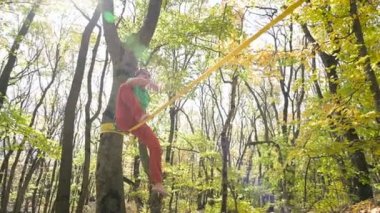 Spor kıyafetleri içinde sakallı, gevşek bir adam ip üzerinde dengede yürüyor. 50 yaşındaki spor aktiviteleri konsepti