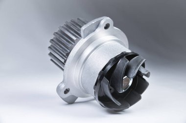 Bir degrade ile gri bir arka plan üzerinde bir motor su pompası soğutma için yeni metal otomobil pompası. Otomobil motoru için yeni yedek parça konsepti