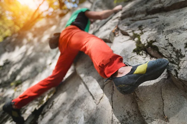 Ein frei gealterter männlicher Kletterer hängt an einer Felswand in einem Wald in den Bergen. Reifes Sportkonzept — Stockfoto