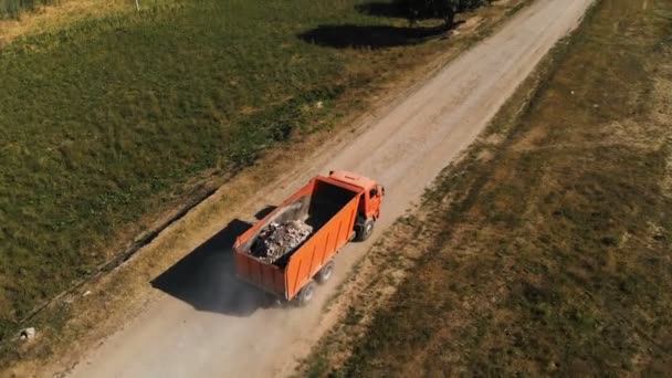 Widok lotniczy ciężarówki. Wywrotka transportująca kamienie i piasek w samochodzie ciężarowym jeździ wzdłuż drogi wiejskiej. Dostawa ładunków logistycznych dla ciężarówek — Wideo stockowe