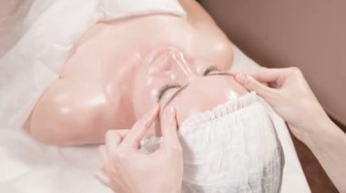 Kapalı Spa yüz masajı. Profesyonel masaj terapisti çekici bir spa salonu müşterisine yüz masajı yapıyor.