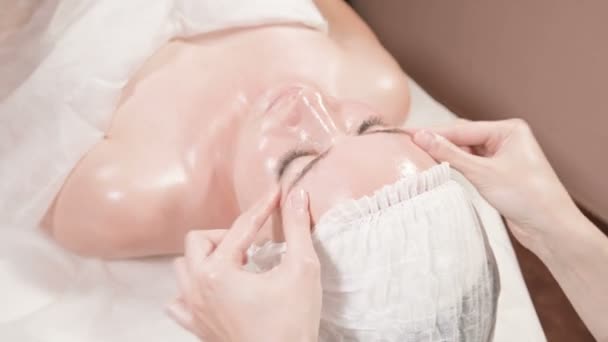 Massaggio facciale Close-up Spa. Ragazza massaggiatrice professionista fa un massaggio facciale rilassante ad un attraente cliente di un salone termale — Video Stock