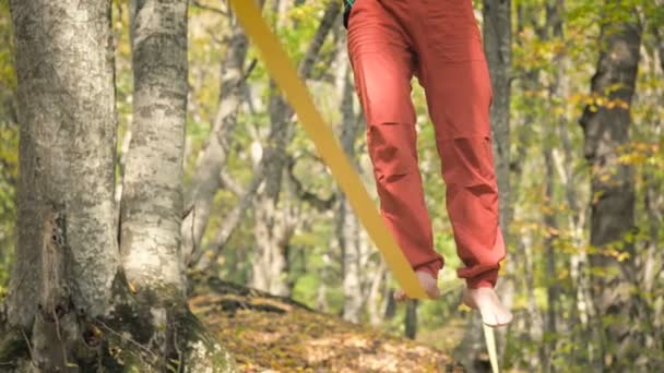 En Slack man åldras med skägg i sportkläder promenader balanserar på slackline. Begreppet idrottsverksamhet vid 50 års ålder. Idrottare fot närbild — Stockvideo