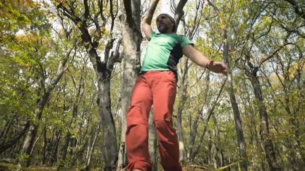 Een Slack man met een baard in sportkleding wandelingen balanceren op de slackline. Het begrip sportactiviteit op 50-jarige leeftijd — Stockvideo