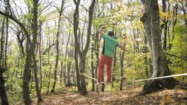 Slackline, spor giyimli sakallı yaşlı bir adam ip üzerinde dengede yürüyor. 50 'li yaşlardaki spor aktiviteleri konsepti