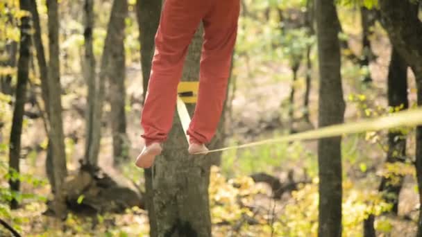 Een Slack man met een baard in sportkleding wandelingen balanceren op de slackline. Het concept van sportactiviteit op de leeftijd van 50 jaar. Atleten voet close-up — Stockvideo