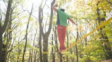 Slackline, spor giyimli sakallı yaşlı bir adam ip üzerinde dengede yürüyor. 50 'li yaşlardaki spor aktiviteleri konsepti