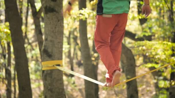 Ein schlaffer Mann mit Bart in Sportbekleidung balanciert auf der Slackline. das Konzept der sportlichen Aktivität im Alter von 50. Athleten Fuß Nahaufnahme — Stockvideo