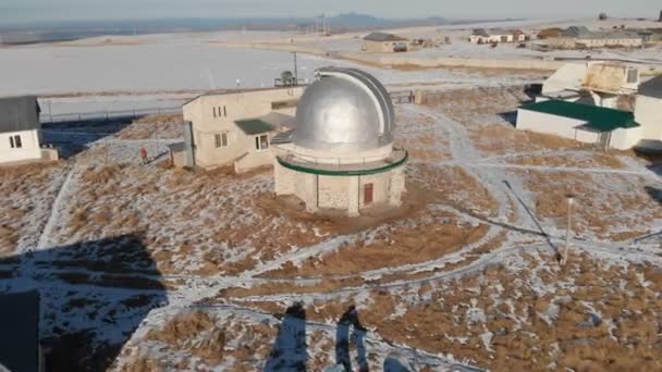 An adult male observatory worker stands on the observation deck of the observation dome and looks into the distance. Aerial view against a clear blue sky. Astronomy science concept — ストック動画