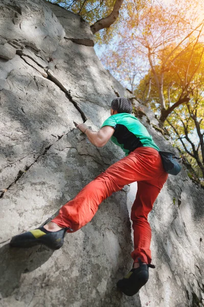 Un alpinist în vârstă liberă atârnă pe un zid de stâncă într-o pădure din munți. Conceptul sportiv matur — Fotografie, imagine de stoc