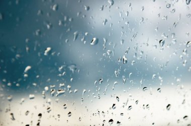 Her iki yağmur ve sisleme soyut görünümü, yağmur damlaları mavi cama cam ve bulanık manzara mavi ve yeşil geçişin üzerinde doğal arka plan damla