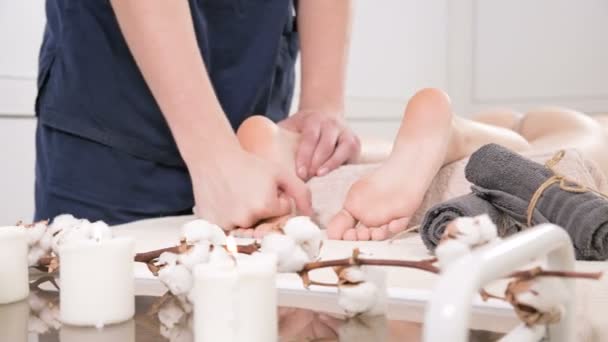 Gros plan d'un physiothérapeute masculin faisant un massage des pieds et des talons à une jeune femme dans un spa de beauté et de santé. Concept de soins des pieds et du corps — Video