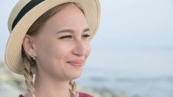 Velká tvář zblízka Portrét atraktivní bílé mladé ženy v slaměném klobouku s copánky narovnává klobouk rukou odvrací pohled — Stock video